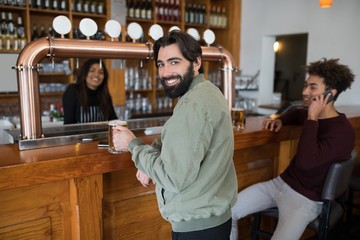 Man having glass of beer at counter in bar