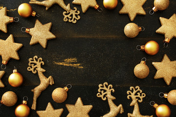 Obraz na płótnie Canvas Top view of golden Christmas decorations (balls, stars, deers) frame over black background with copy space