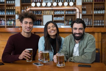 Smiling friends having glass of beer in bar