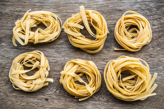 Italian pasta tagliatelle nest on wooden background
