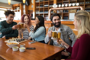 Friends toasting glass of beer in bar