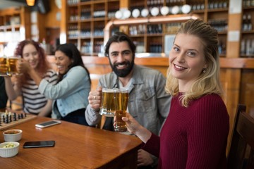 Friends toasting glass of beer in bar