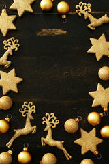 Top view of golden Christmas decorations (balls, stars, deers) frame over black background with copy space