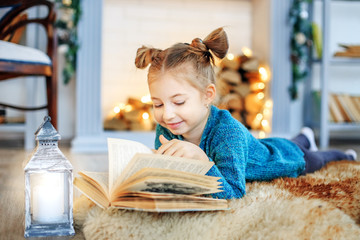 A smiling child reads a book at home. Concept New Year, Merry Christmas, holiday, vacation, winter, childhood.