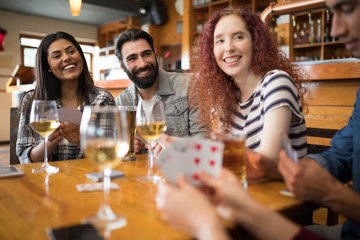 Happy friends playing cards while having glass of beer