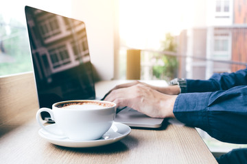 Human hand working on keyboard laptop with coffee in morning.