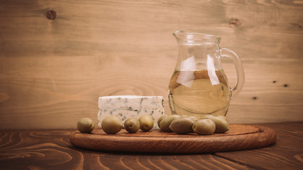 Olive oil with blue cheese and olives on wooden board