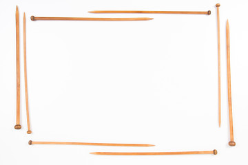 Wooden knitting needles arranged as frame on white background