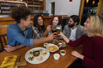Friends toasting glass of beer in bar
