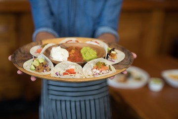 Waiter holding plate of Mexican food in bar
