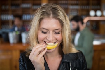 Beautiful woman biting into lemon wedge after having tequila