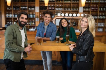 Smiling friends having glass of beer in bar
