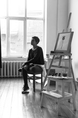 Female artist in her spacious white studio working with watercolor painting.  Natural lighting. Disclosure of creativity concept. Vertical composition. Black and white image