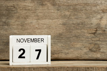 White block calendar present date 27 and month November on wood background
