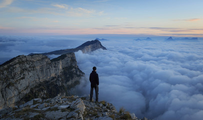 Man looking over a sea of clouds in the mountains. Vercors, France.