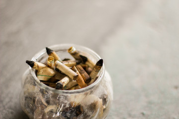 smoked cigarettes butts in the glass ashtray with grey background