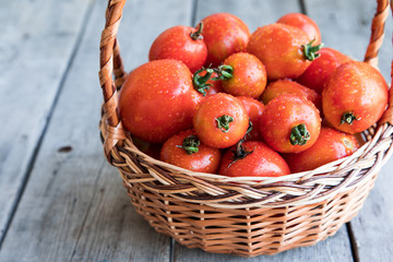 Fototapeta na wymiar Juicy ripe organic tomatoes in a basket on wooden background