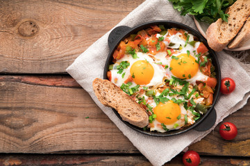 Shakshuka with eggs, tomato, and parsley in a iron pan. Shakshuka - traditional israeli tomato stew with eggs