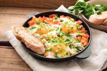 Shakshuka with eggs, tomato, and parsley in a iron pan. Shakshuka - traditional israeli tomato stew with eggs