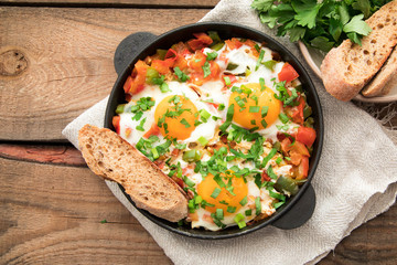 Shakshuka with eggs, tomato, and parsley in a iron pan. Shakshuka - traditional israeli tomato stew with eggs