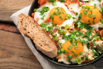 Shakshuka with eggs, tomato, and parsley in a iron pan. Shakshuka - traditional israeli tomato stew with eggs