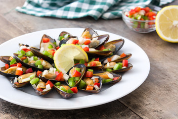 Steamed mussels with peppers and onion on wooden table