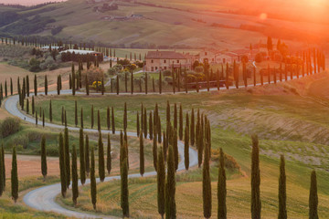 Obraz premium Magnificent spring landscape at sunset.Beautiful view of typical tuscan farm house, green wave hills, cypresses trees, magical sunlight, beautiful golden fields and meadows.Tuscany, Italy, Europe