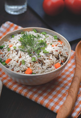 boiled mix rice in a white bowl on the dark table with a wood spoon