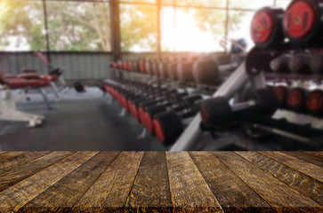 Wooden table on blurred background of fitness gym interior of modern club with equipment for your photomontage or product display.