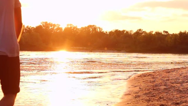 Happy couple in love walk on water near beach and kiss each other during sunset in spring / summer.