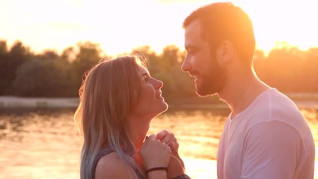 Male / man kissing hands of female / woman / girl during sunset in spring / summer near river / water. Date concept