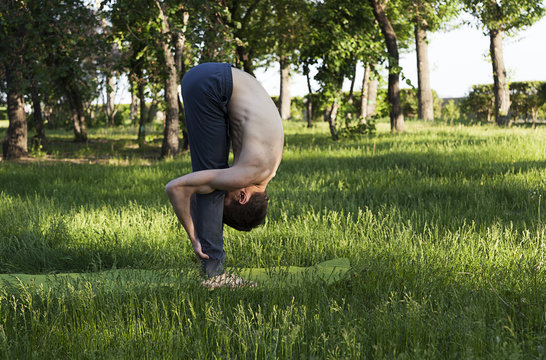 practice of yoga and gymnastics. young man in the park