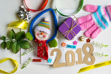 Fototapeta na wymiar notepad with snowman doll and pencil on wood background for happy new year image. And welcome new year photo