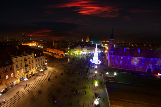 Panorama of Warsaw at night - view of the Castle Square with a Christmas tree and a crowd of people