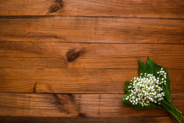 Lilies of the valley on a wooden old background and free space for your text.
