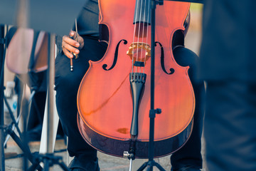 close up of male cellist holding cello at an outdoor concert