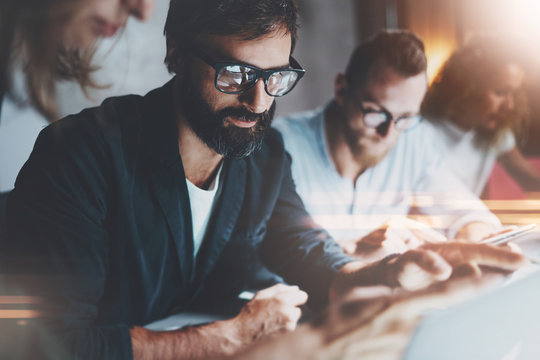 Group of young entrepreneurs are looking for a business solution during work process at night office.Business people meeting concept.Blurred background.Horizontal.