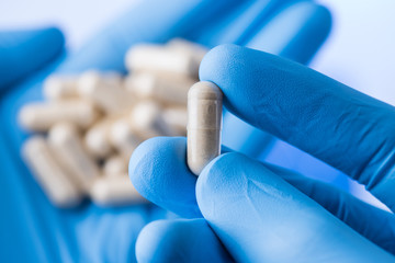 Scientist hands in gloves hold pills, new pill research concept