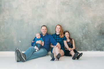 Naklejka premium Happy family portrait siting on gray background white floor room sunny day