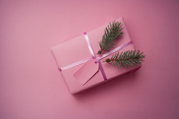 Christmas gift in a pink paper on a pink background with place for text. Flat lay. Original...
