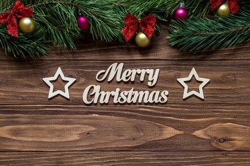 Merry Christmas title on the center of the wooden background and two beautiful stars with pine tree branches on the top and tinsel.