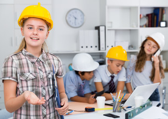 Girl in color helmet builder near notebook