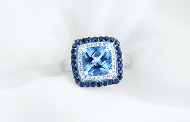Ring with blue topaz and diamonds on soft white background