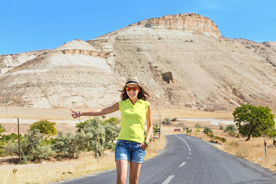 Woman hitchhiking on a road at the background of desert and mountains in Cappadocia