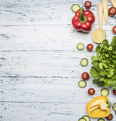 Ingredients for cooking vegetarian salad, bell peppers, cucumbers, cherry tomatoes, lettuce leaves, salt and black pepper, lime lined on a white rustic background, top view, , border, space  text