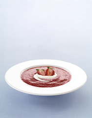 Delicious compot with red fruits and whipped cream in a plate