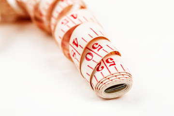 Curled measuring tape on a white background, closeup shot