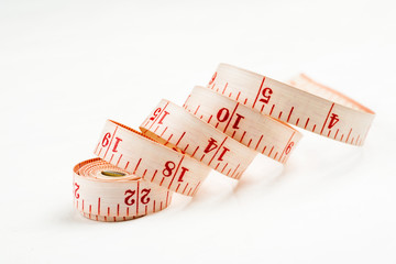 Curled measuring tape on a white background, closeup shot