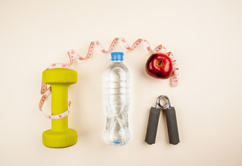 Sports equipment with bottle of water, measuring tape and red apple top view