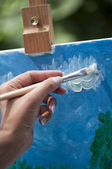 Female artist working on a painting in a park. Selective focus on foreground